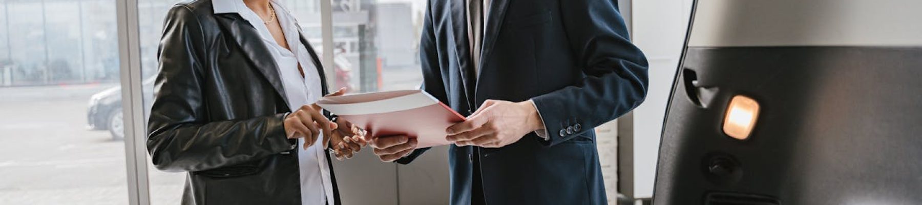 A man and woman wearing formal clothing and discussing work on a document